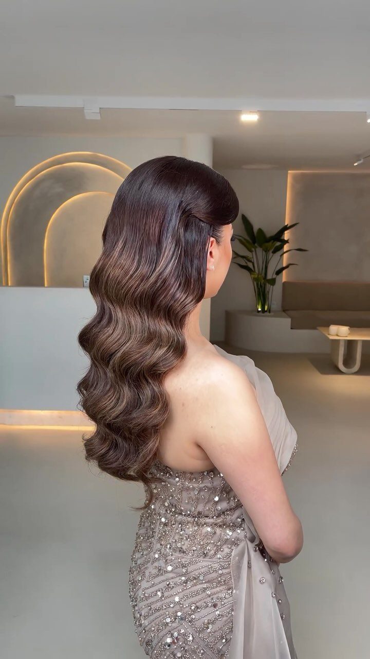 Woman in silver dress wearing long sculpted waves and a voluminous formal hairstyle