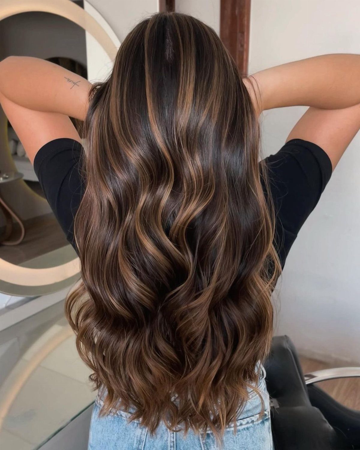Long brunette waves with golden highlights cascading down the back