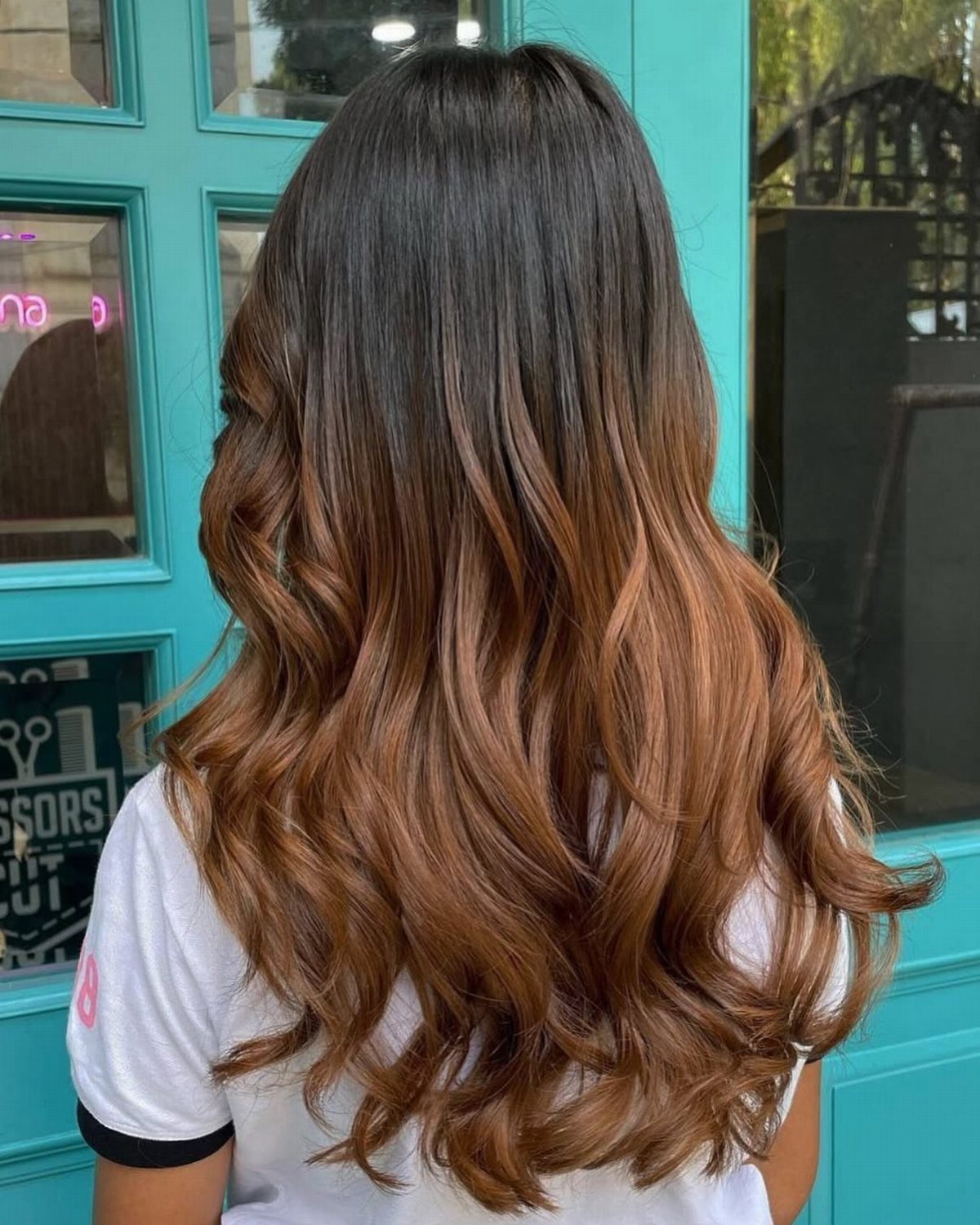 Long wavy brown hair graduates from dark roots to golden-brown ends