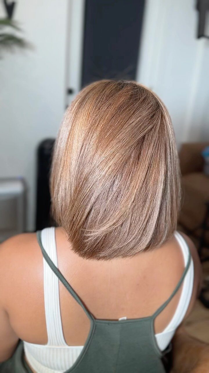 Short light brown bob with warm golden tones, viewed from behind in a salon