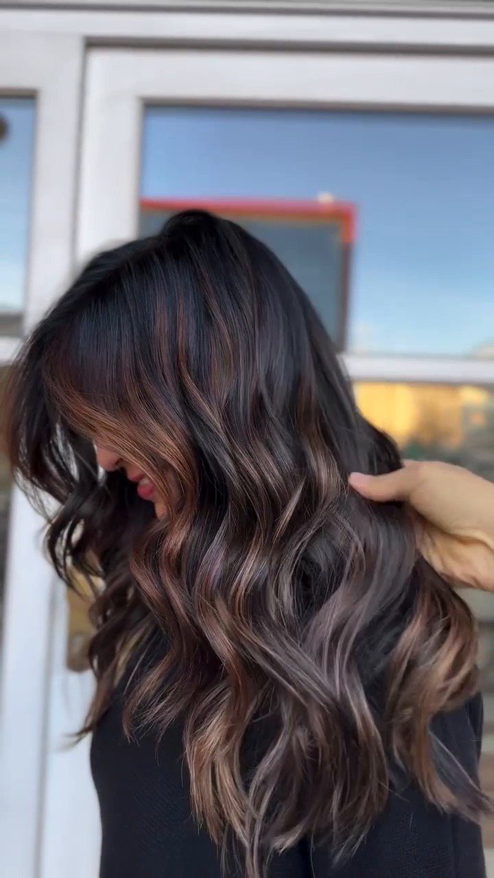 Wavy dark brown hair with warm amber balayage highlights