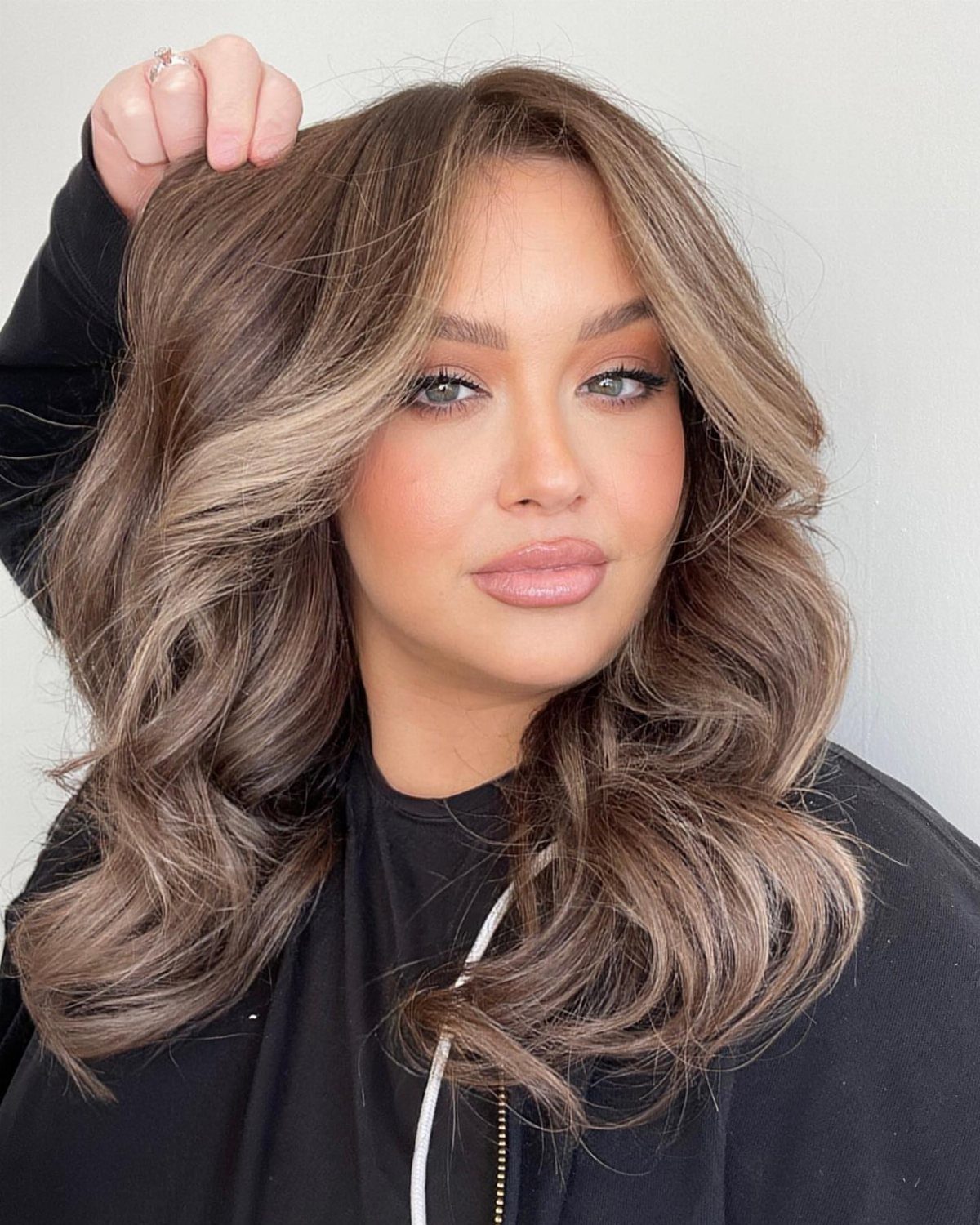 Woman showing voluminous brown sugar brunette hair with beige tones and soft curls