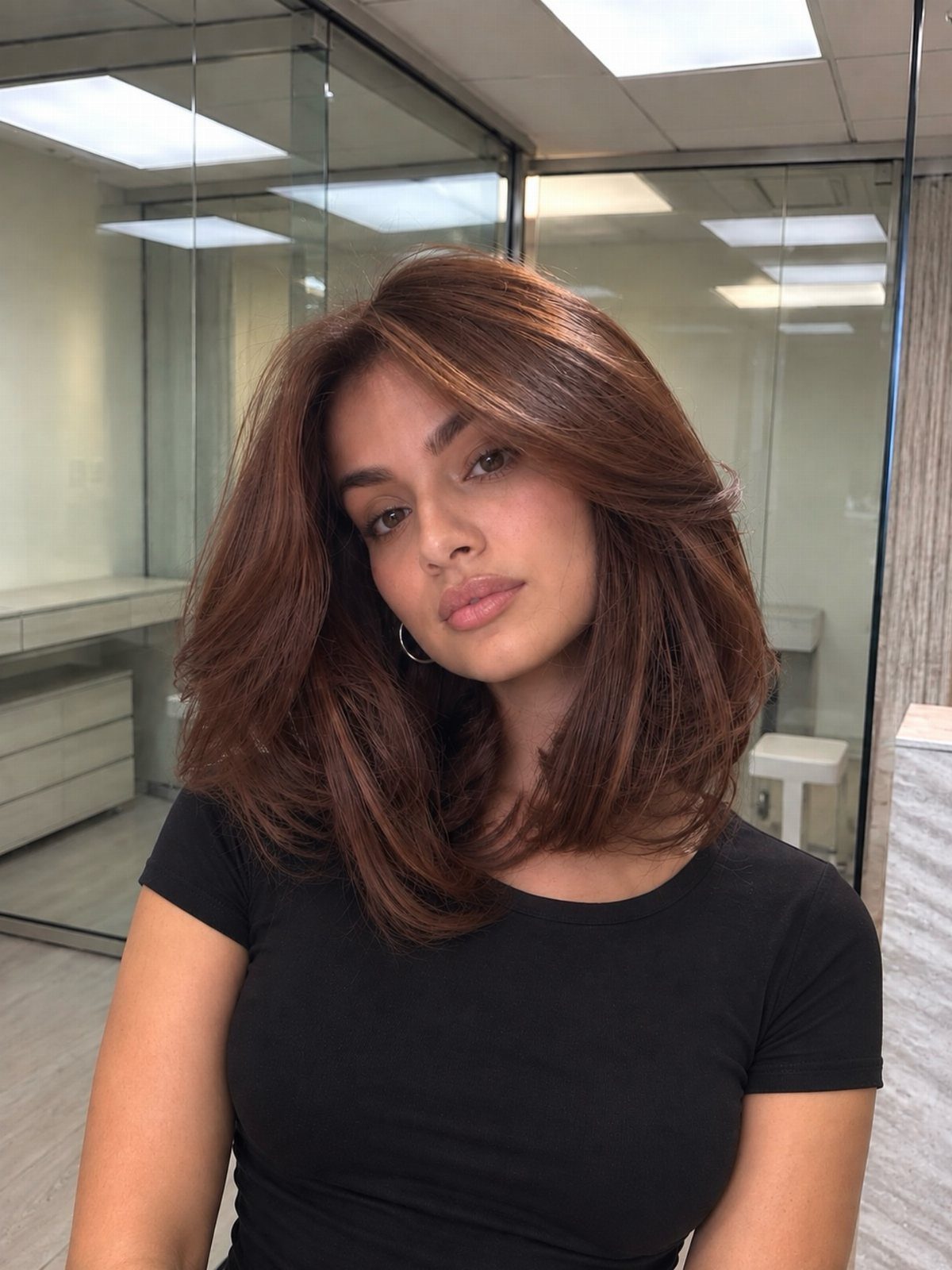 Woman posing with layered chestnut-brown hair and subtle reddish tones