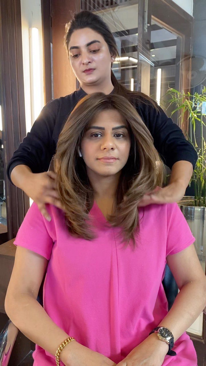Woman with layered brown hair and lighter highlights seated in a salon