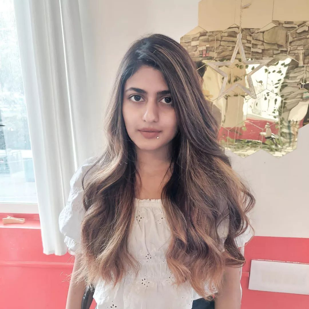 Woman with long, wavy light brown hair and subtle lighter strands