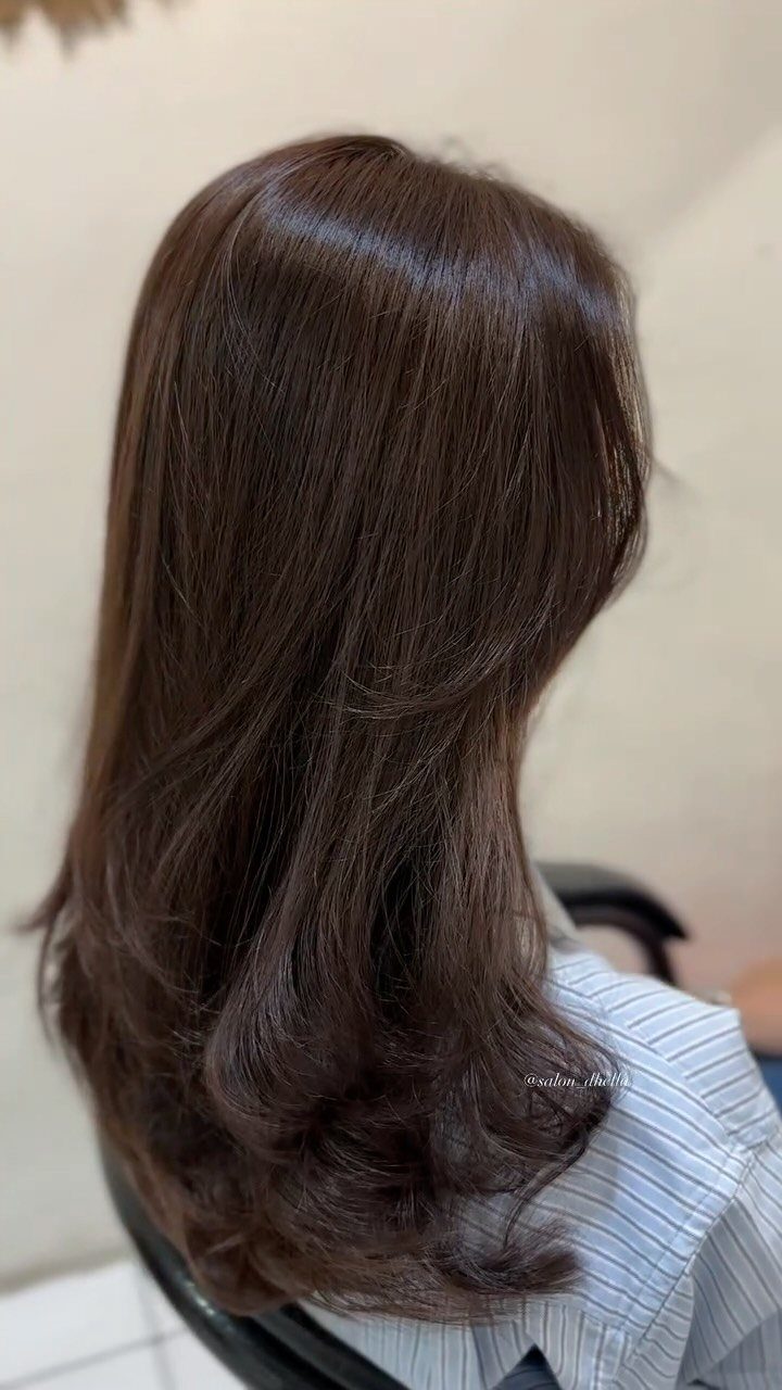 Layered medium brown hair falls to the shoulders with softly curled ends