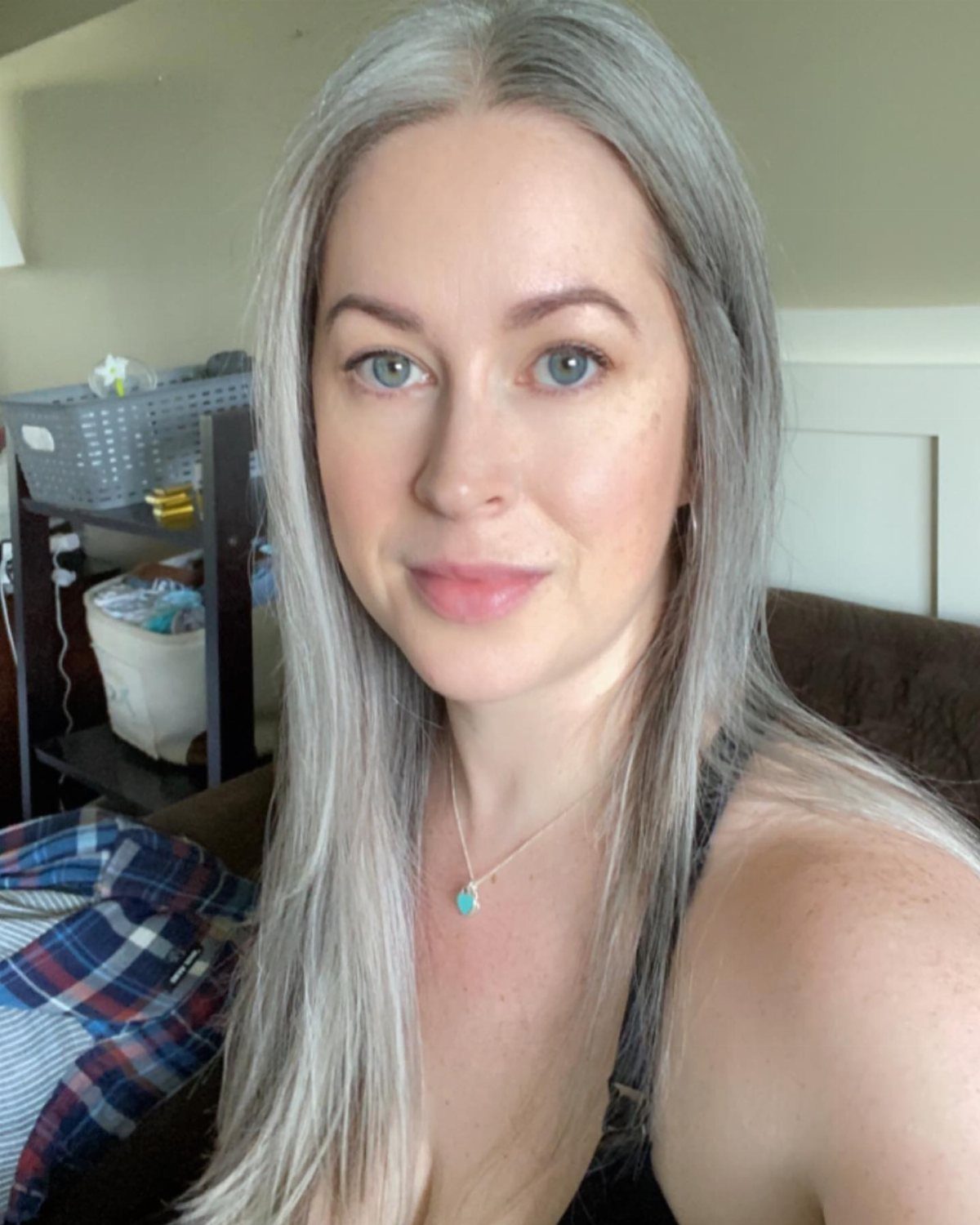 Woman poses indoors with long, straight silver-gray hair