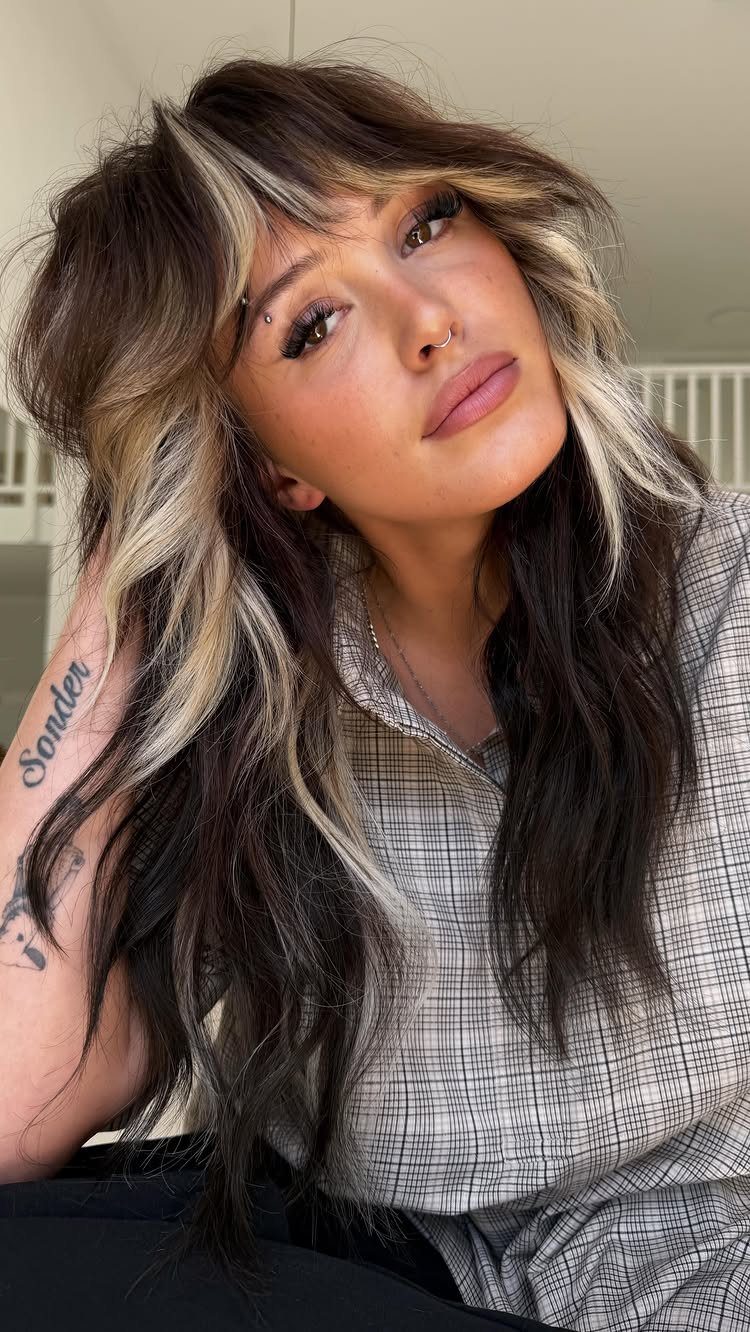 Woman with long dark hair and blonde streaks framing her face