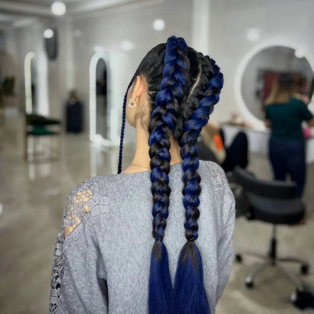 Vivid blue braids hang down the back of a person in a salon