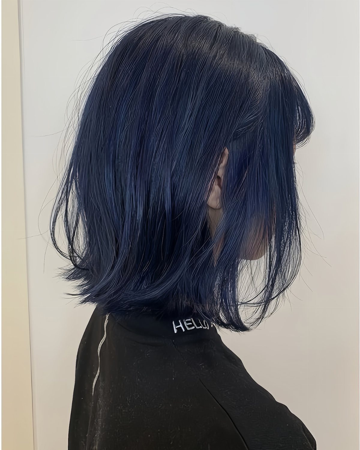 Layered dark bob with a faint blue sheen against a pale wall
