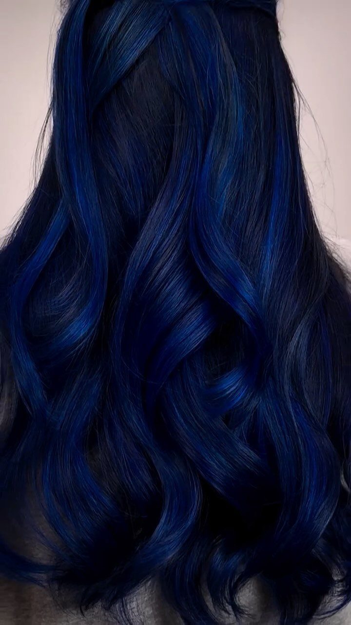 Long glossy dark blue hair falls in loose, voluminous curls