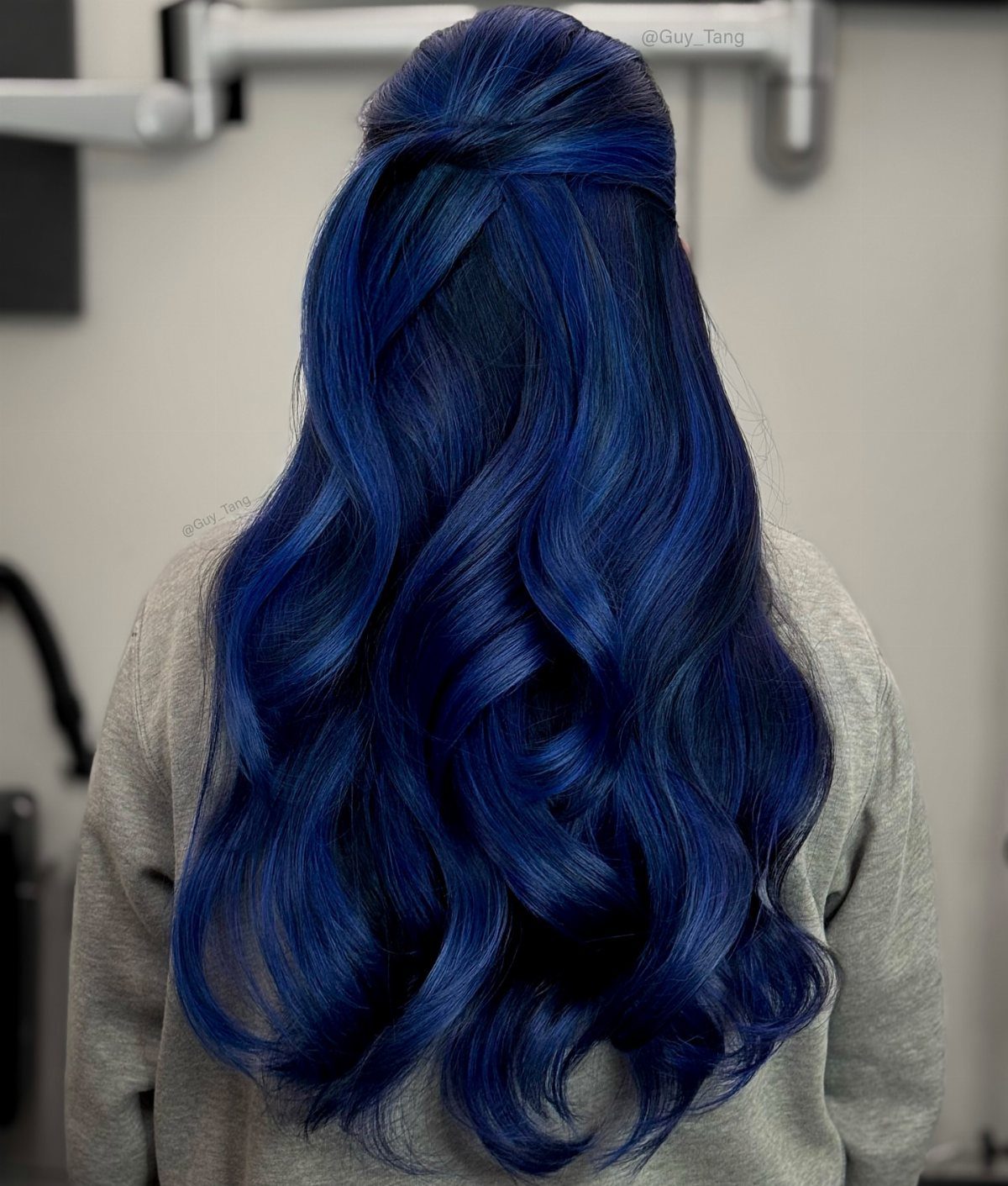 Deep indigo waves cascade down a model’s back in a salon