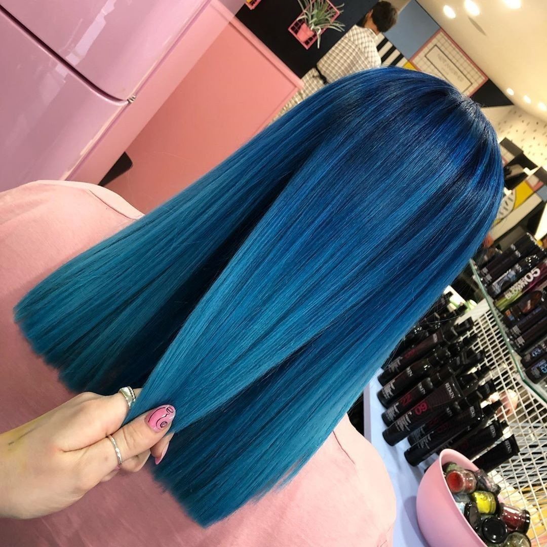 Long vivid blue hair with teal ends held out in a salon