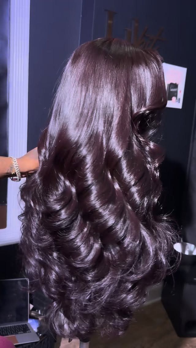 Long dark-purple hair falls in glossy, voluminous cascading waves