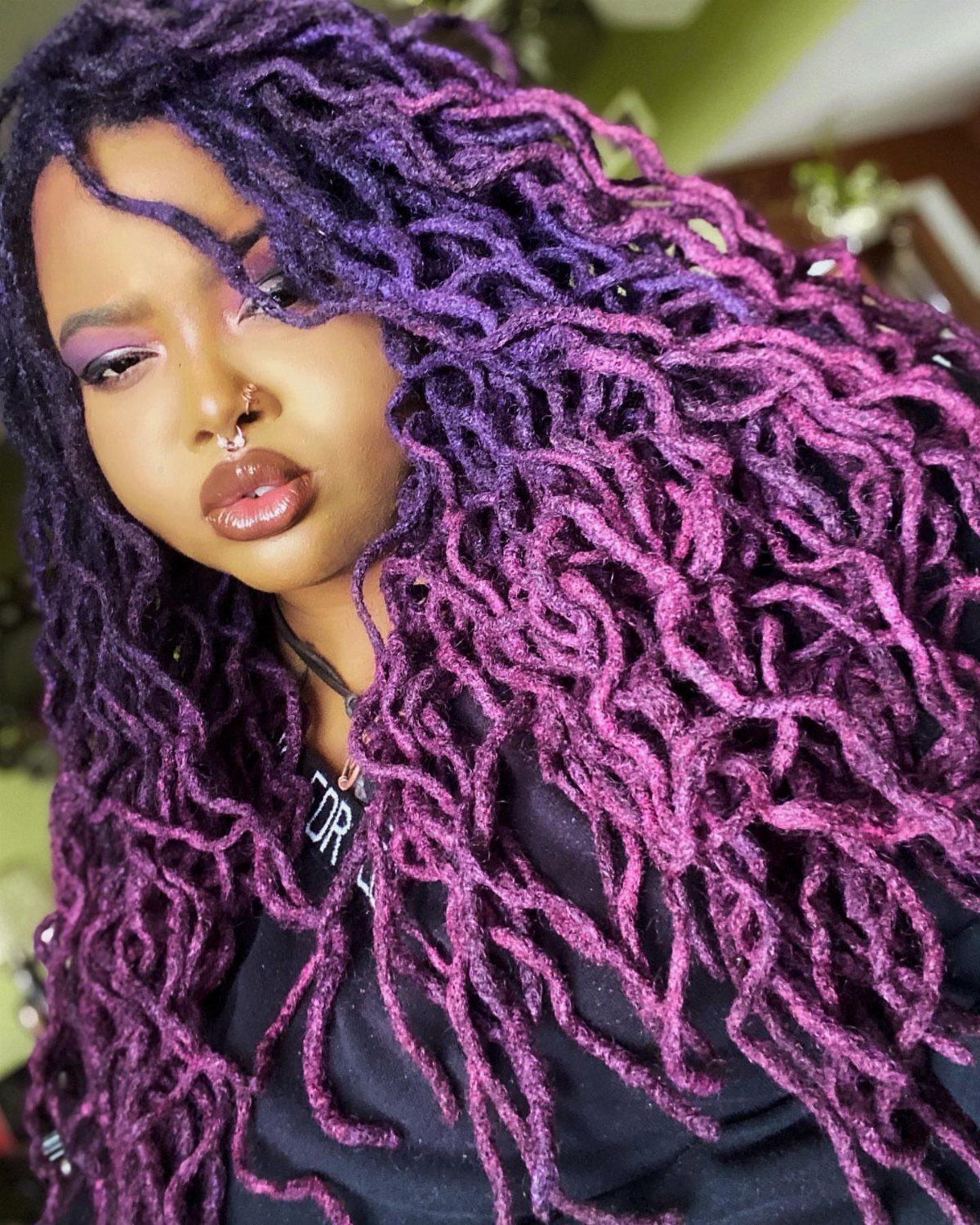 Woman wearing long voluminous purple hair twists over a black top