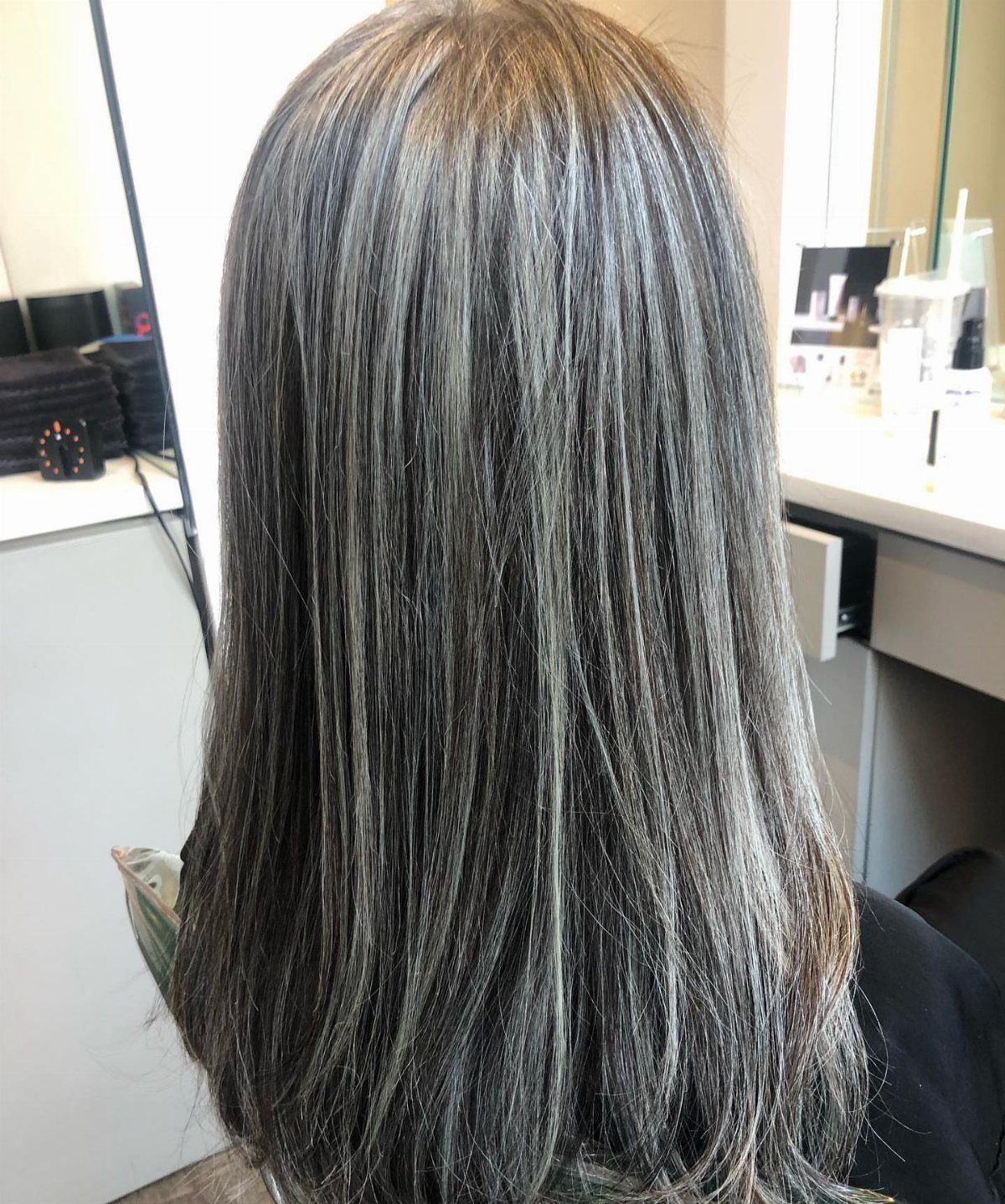 Long dark hair with fine silver-gray highlights in a salon
