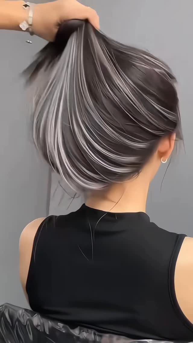 Dark hair with silver-grey streaks swept upward by a hand