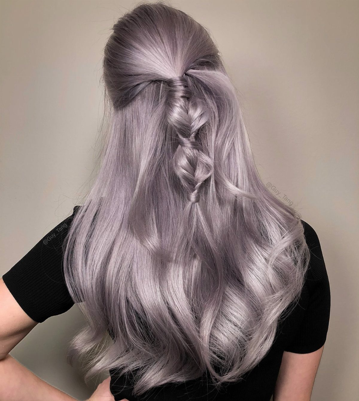 Long silver-lavender hair with dark roots in a braided half-up style