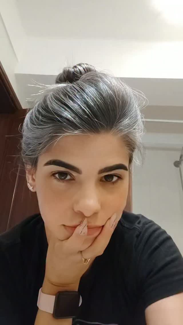 Silvery grey hair swept back into a bun on a person posing indoors.