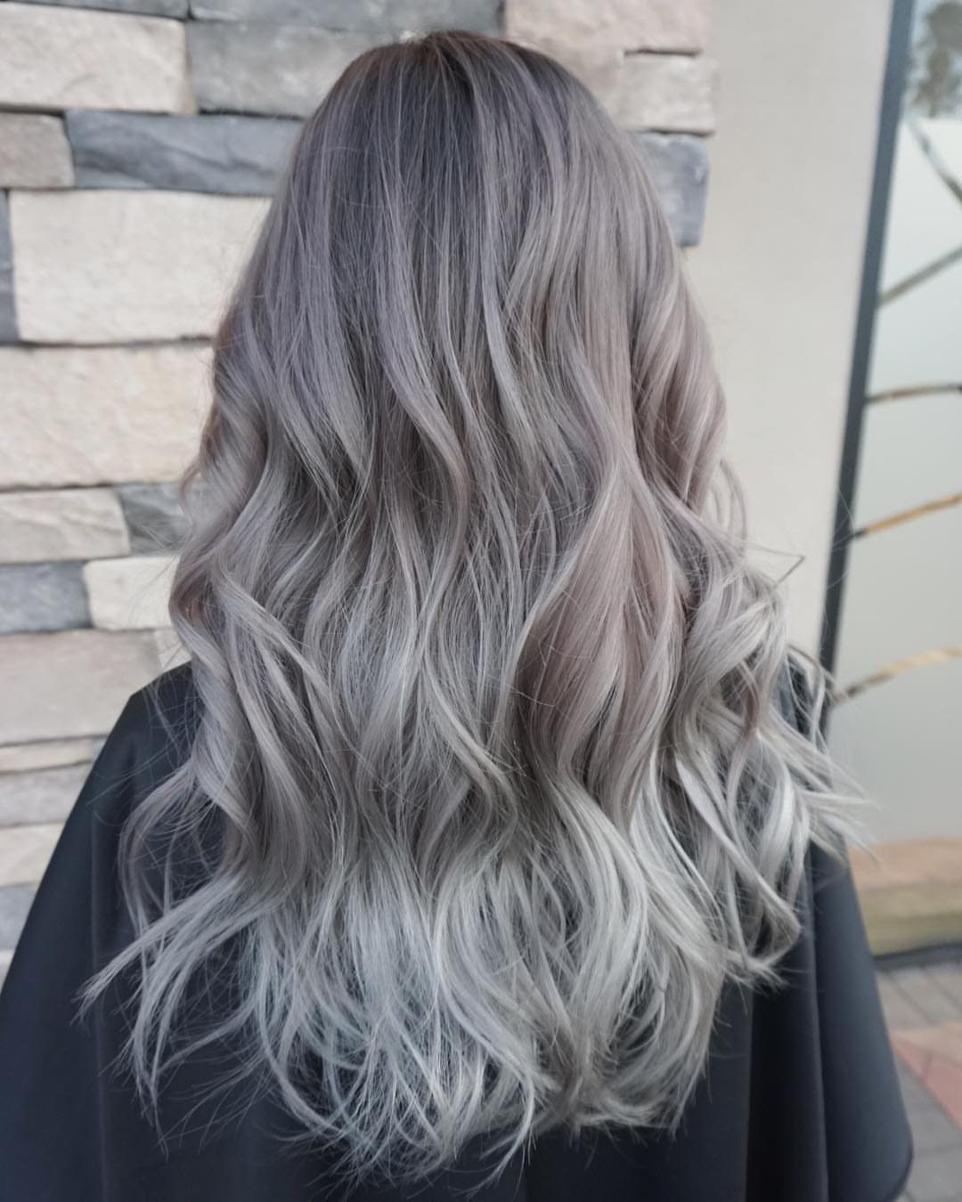 Long wavy smoky silver-gray hair with darker roots and lighter strands