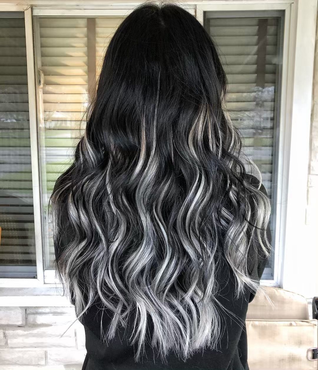 Black wavy hair with silver and blonde streaks against a shuttered window