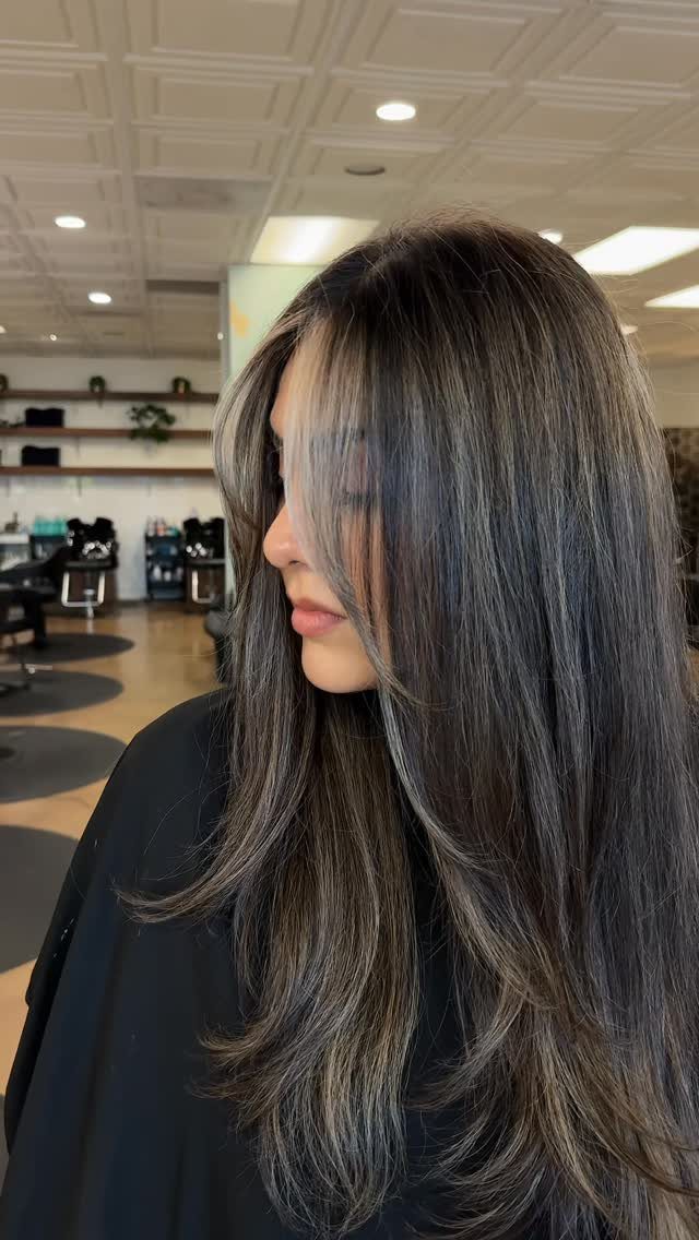 Long dark brunette hair blends into cool ash-gray ends in layered waves