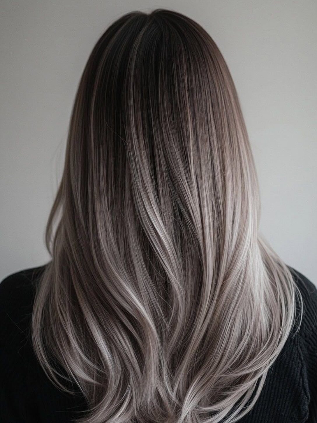 Long hair fades from dark brown roots into wavy metallic silver-gray lengths