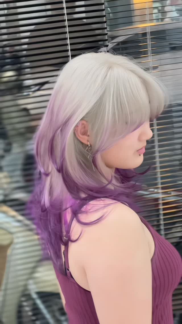 Layered silver hair fades into lavender and purple ends on a woman