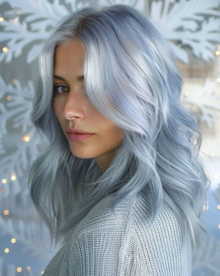 Woman with long, wavy silver-blue dyed hair wearing a light gray knit sweater