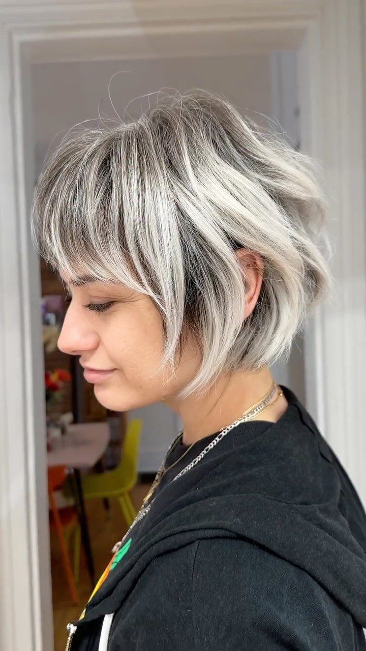 Woman with short silver-blonde highlights in a layered bob indoors