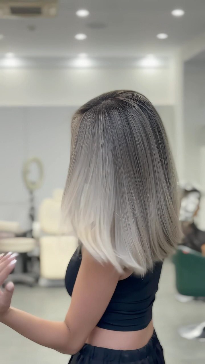 Shoulder-length silver-gray hair with dark roots, shown from behind in a salon