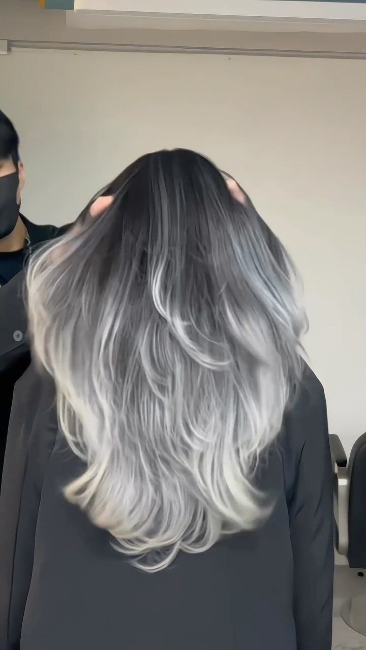 Long charcoal-to-silver gray hair with wavy pale ends in a salon