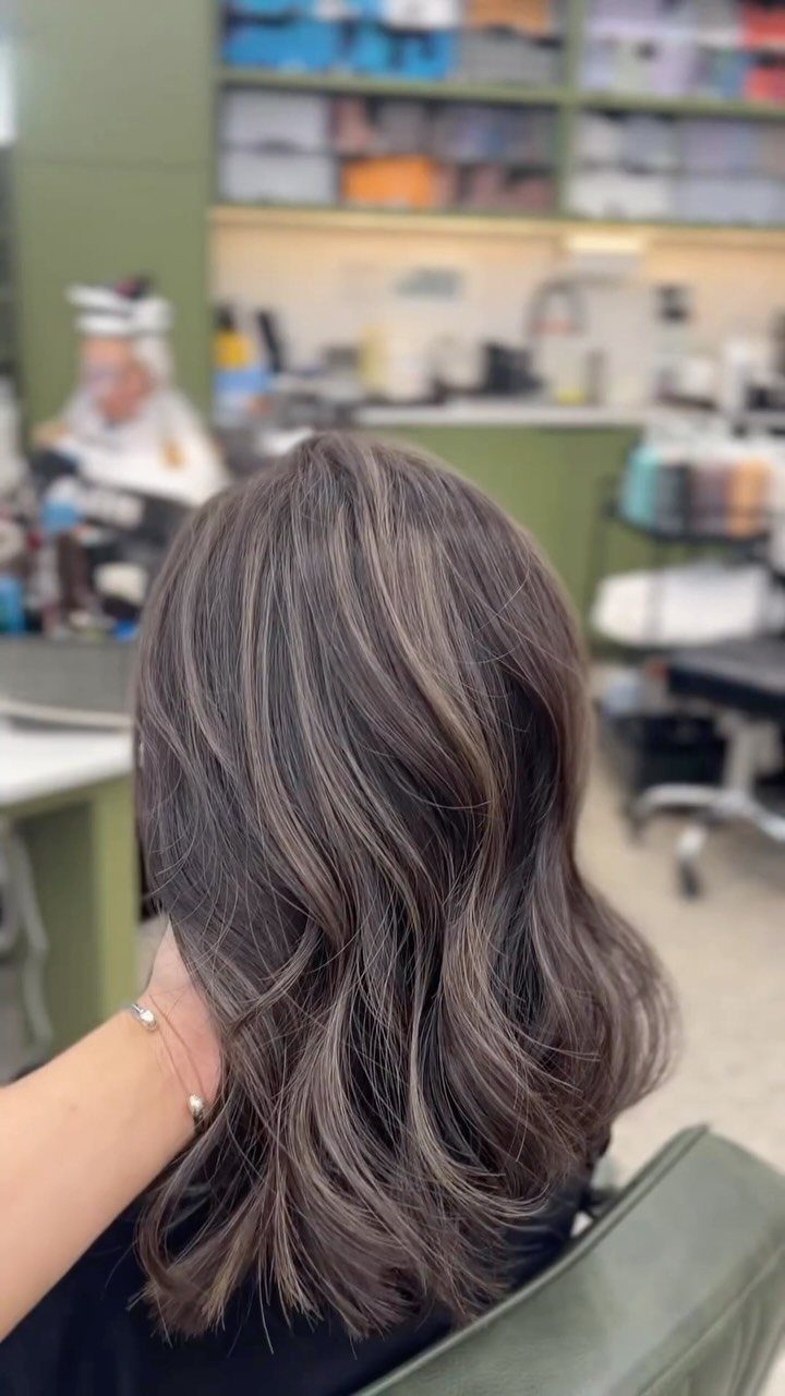Glossy gray-brown hair with silver strands styled in loose waves at a salon