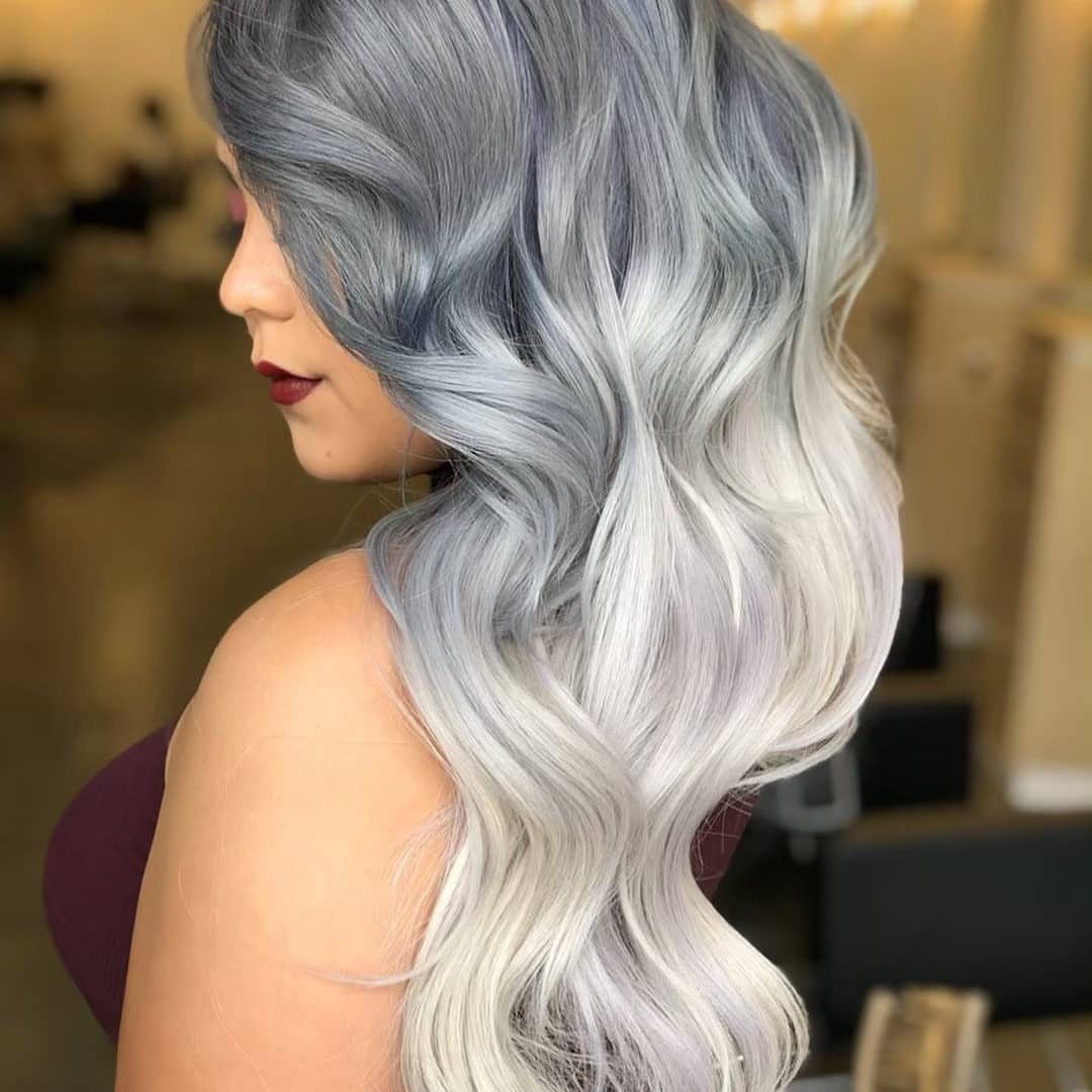 Wavy hair fades from dark gray roots into icy silvery blonde ends