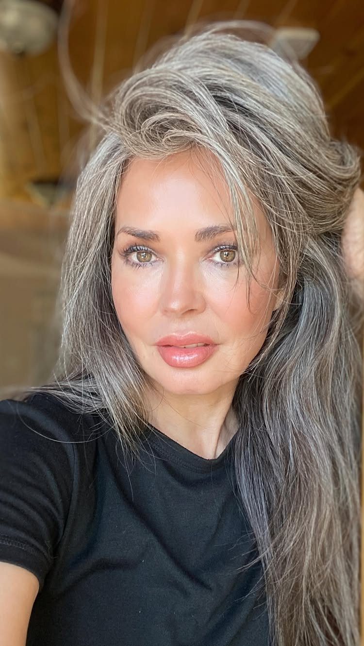 Woman with long, wavy silver-gray hair and darker strands wearing a black shirt