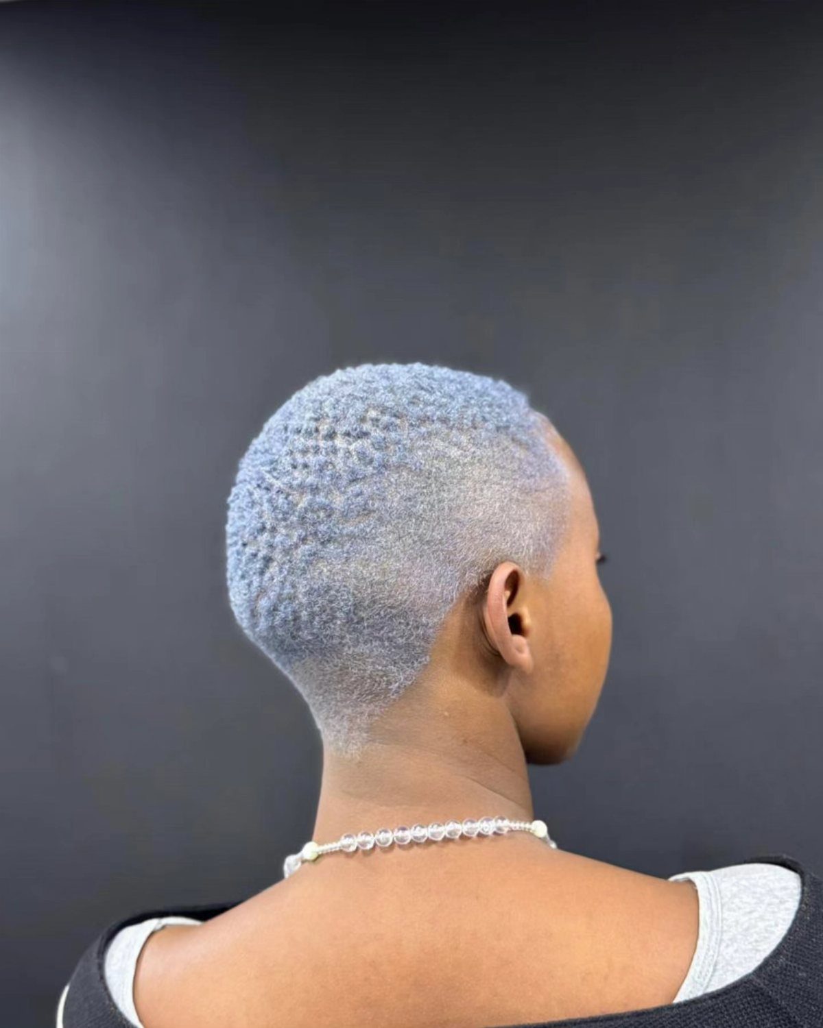 Short silver-gray cropped hair shown from behind with a tapered neckline