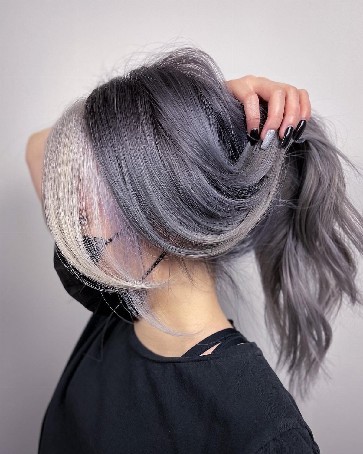 Long silver-gray hair with dark roots and pale face-framing streaks