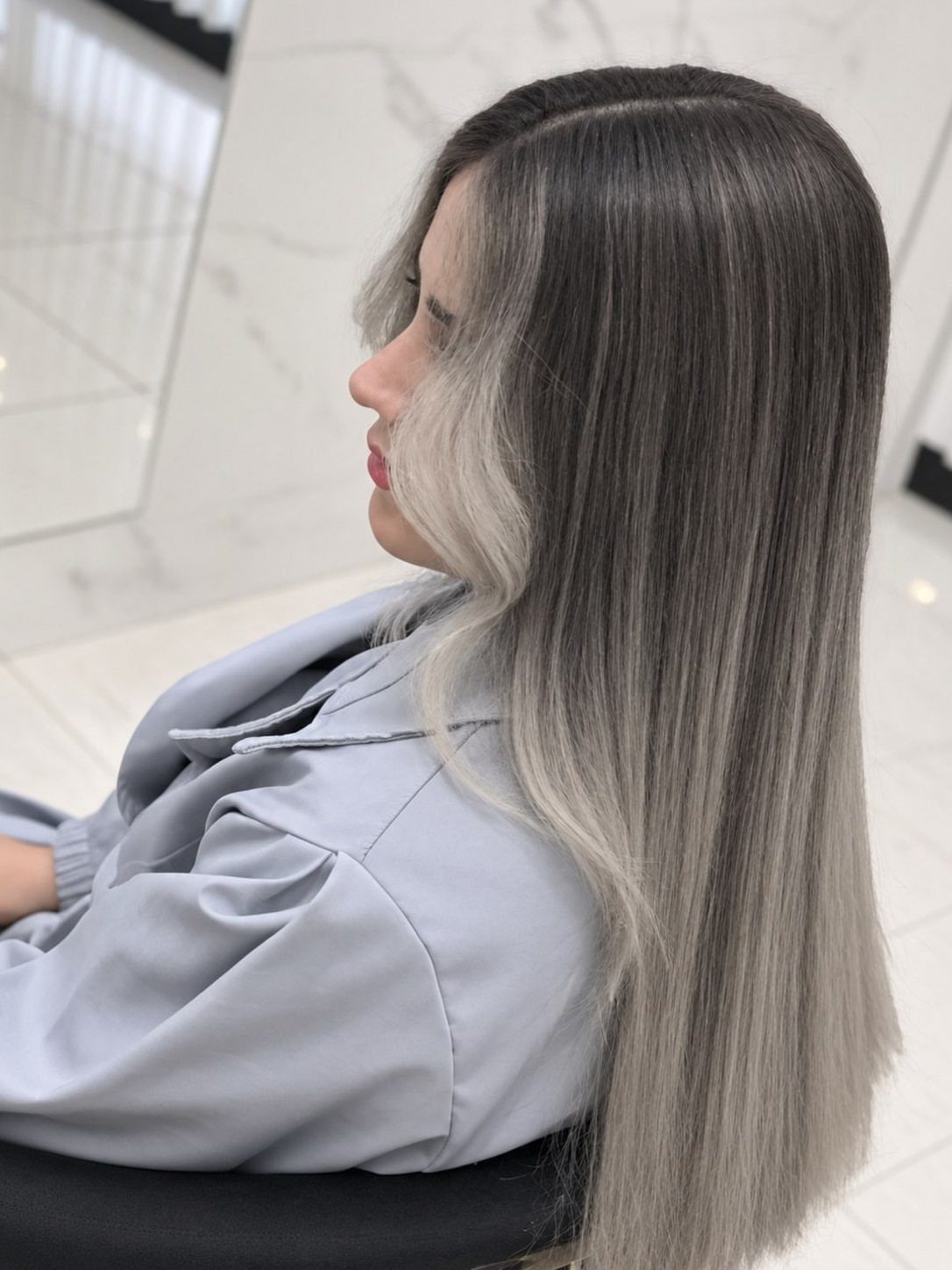 Long gray-brown hair with a pale ash money piece framing the face