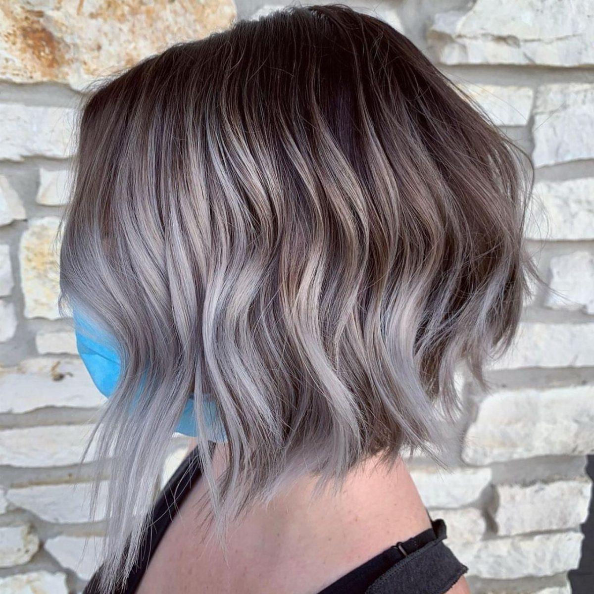 Short wavy hair fades from dark brown roots to smoky silver-gray lengths