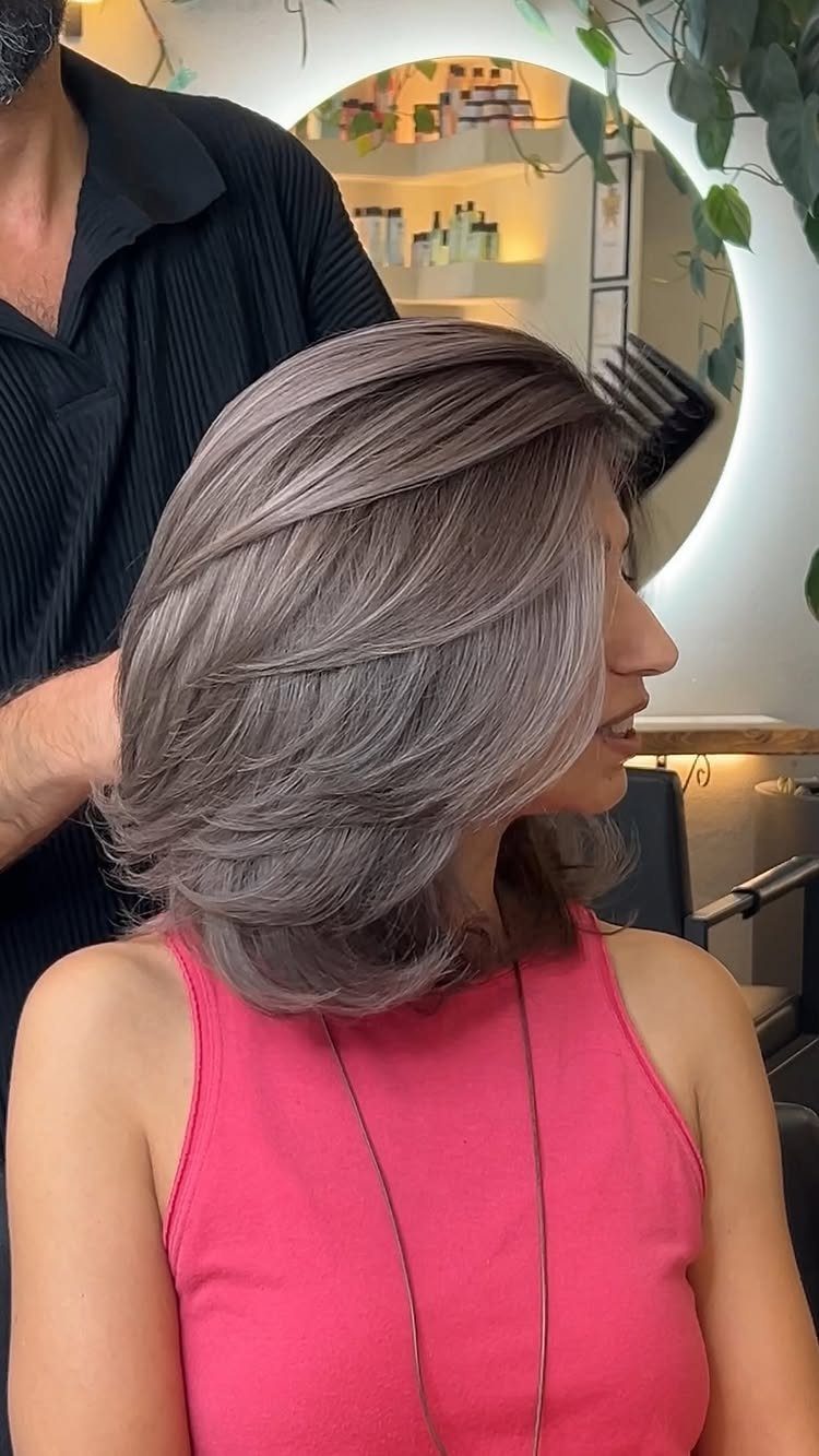 Woman showing a layered, side-parted gray hairstyle in a salon