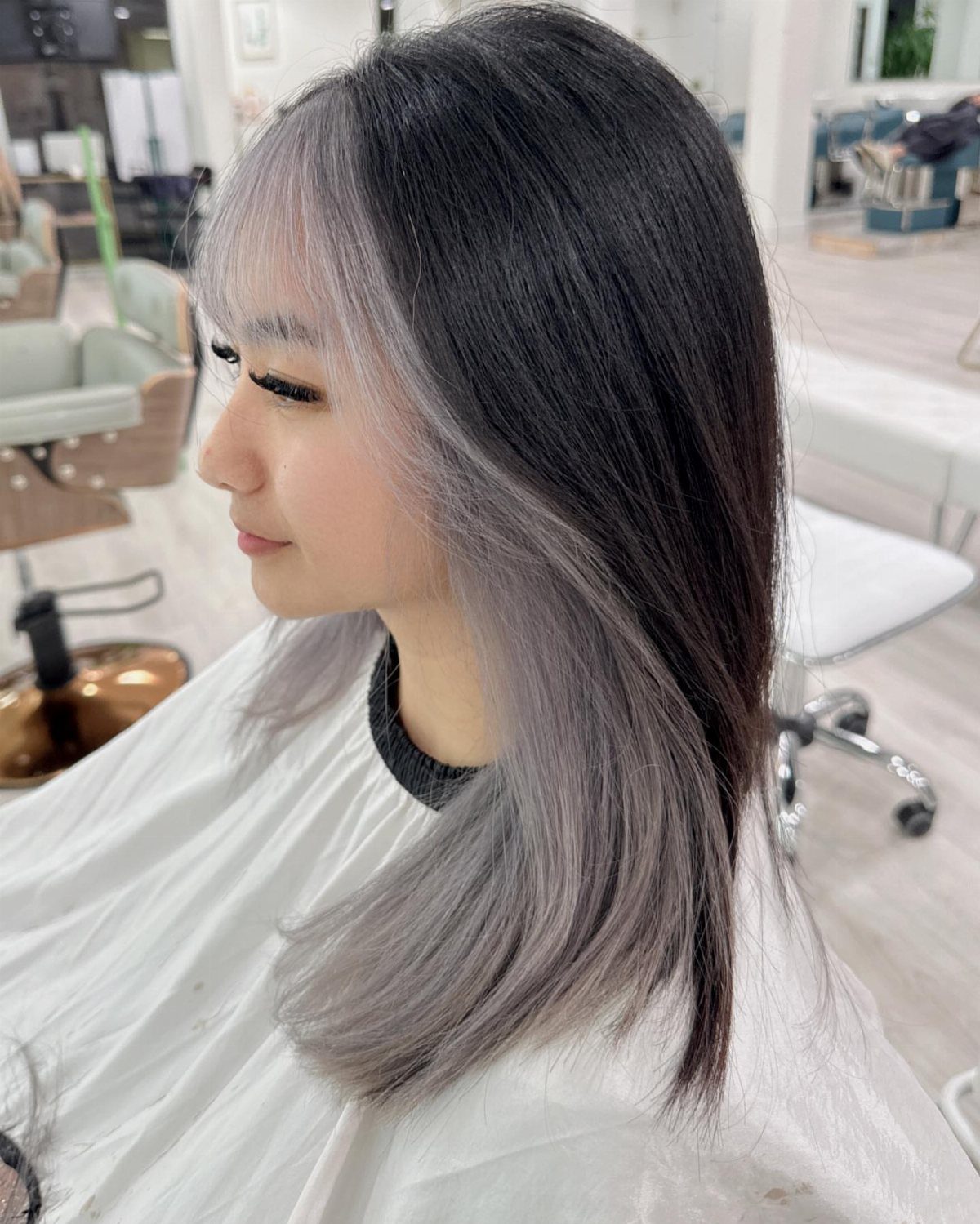 Woman with dark hair and broad silver-gray panels in a salon