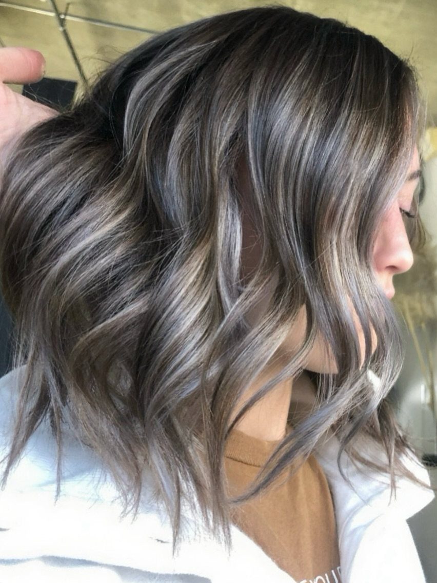Wavy dark brown hair with cool gray highlights lifted to show blended roots