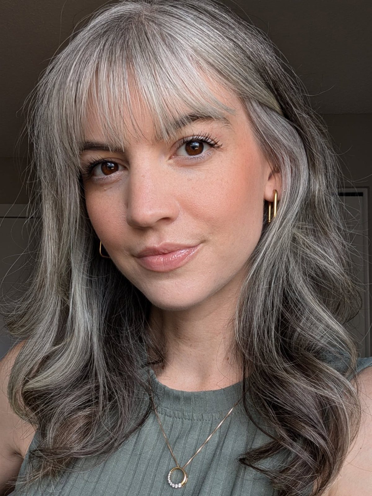 Woman with long layered graphite gray hair blended with darker roots