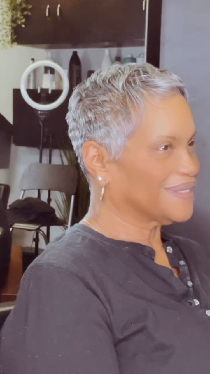 Woman with a short silver-gray pixie haircut sitting in a salon