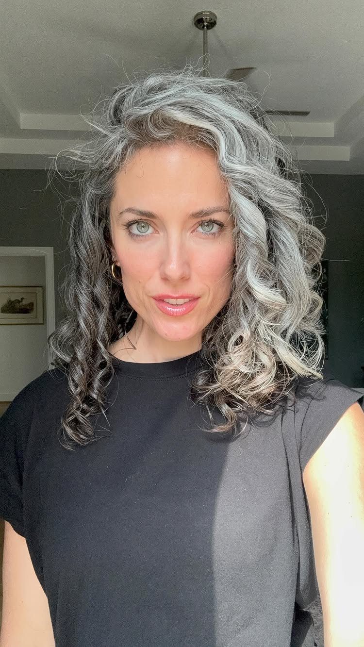 Woman with wavy salt-and-pepper hair and bright silver strands framing her face