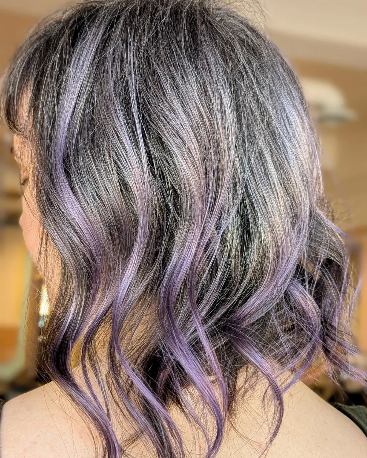 Wavy silver-gray hair with dark roots and lavender-purple strands