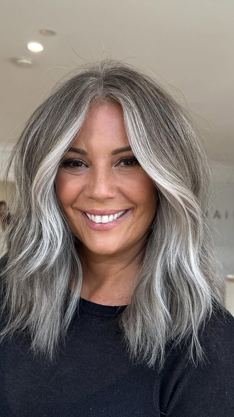 Woman with long dark hair woven with silver strands in loose waves