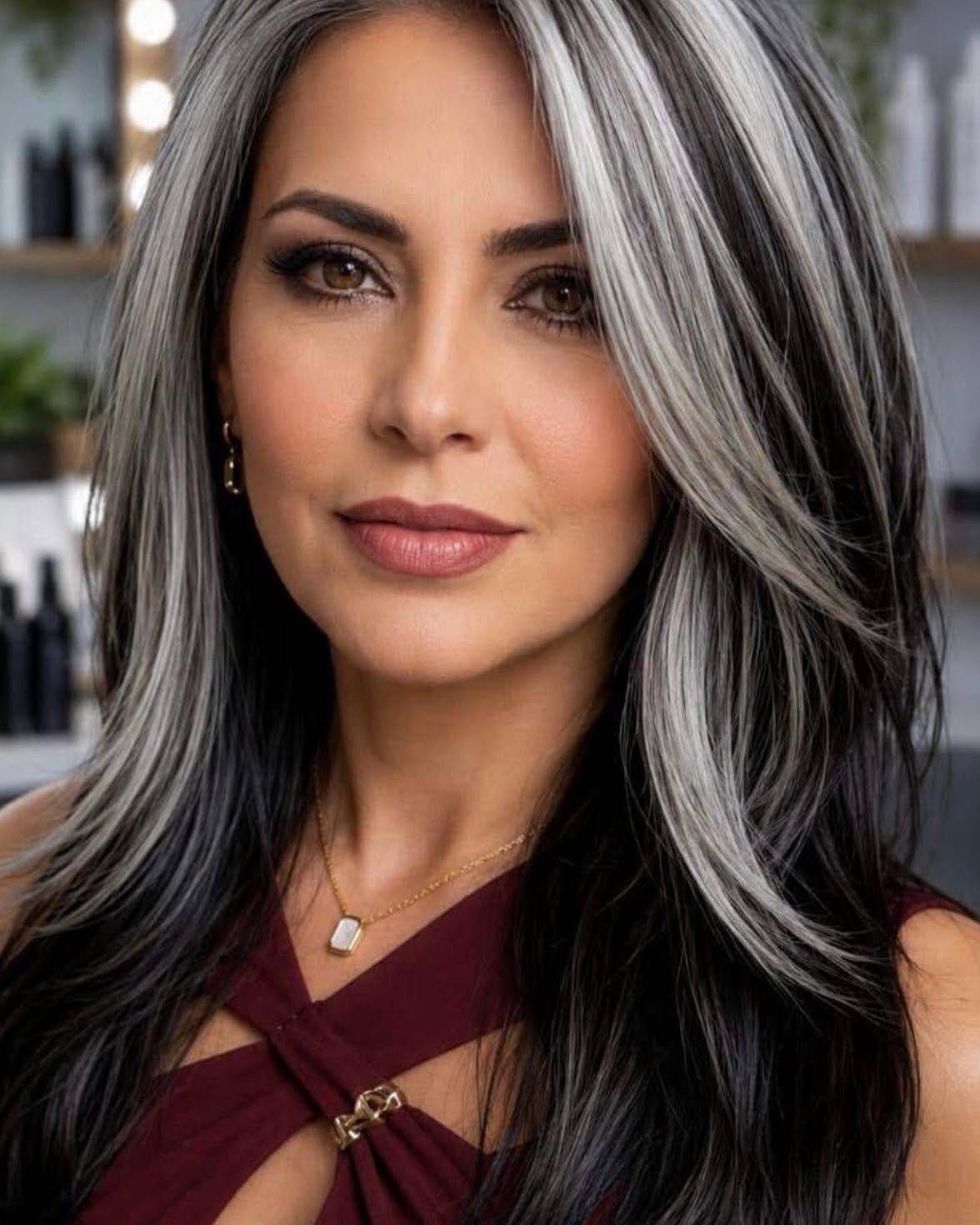 Woman with long dark waves and prominent silver highlights framing her face