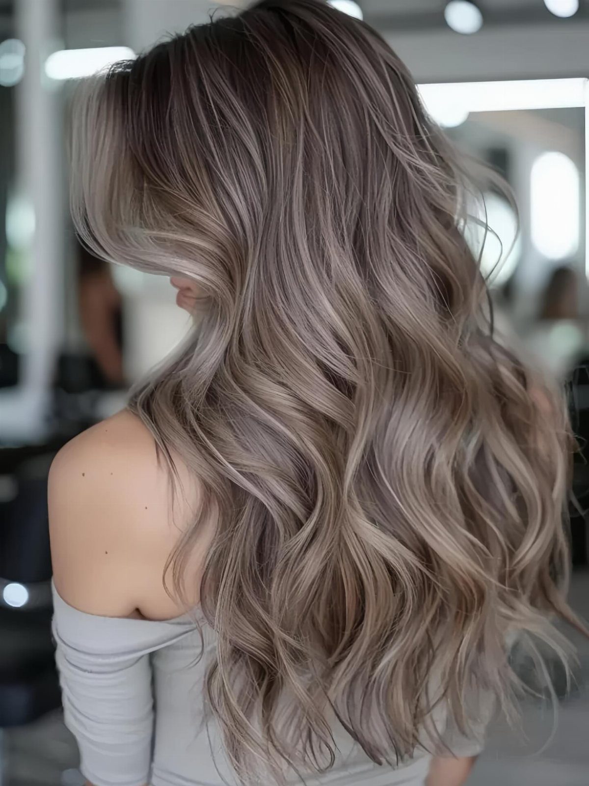 Long wavy dark hair with smoky ash-gray highlights in a salon