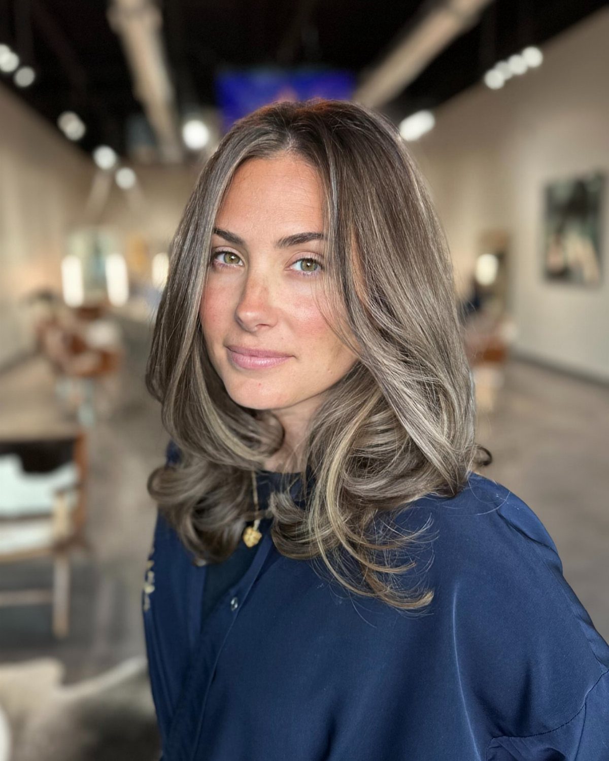 Woman with long dark layered hair and soft silver-gray highlights